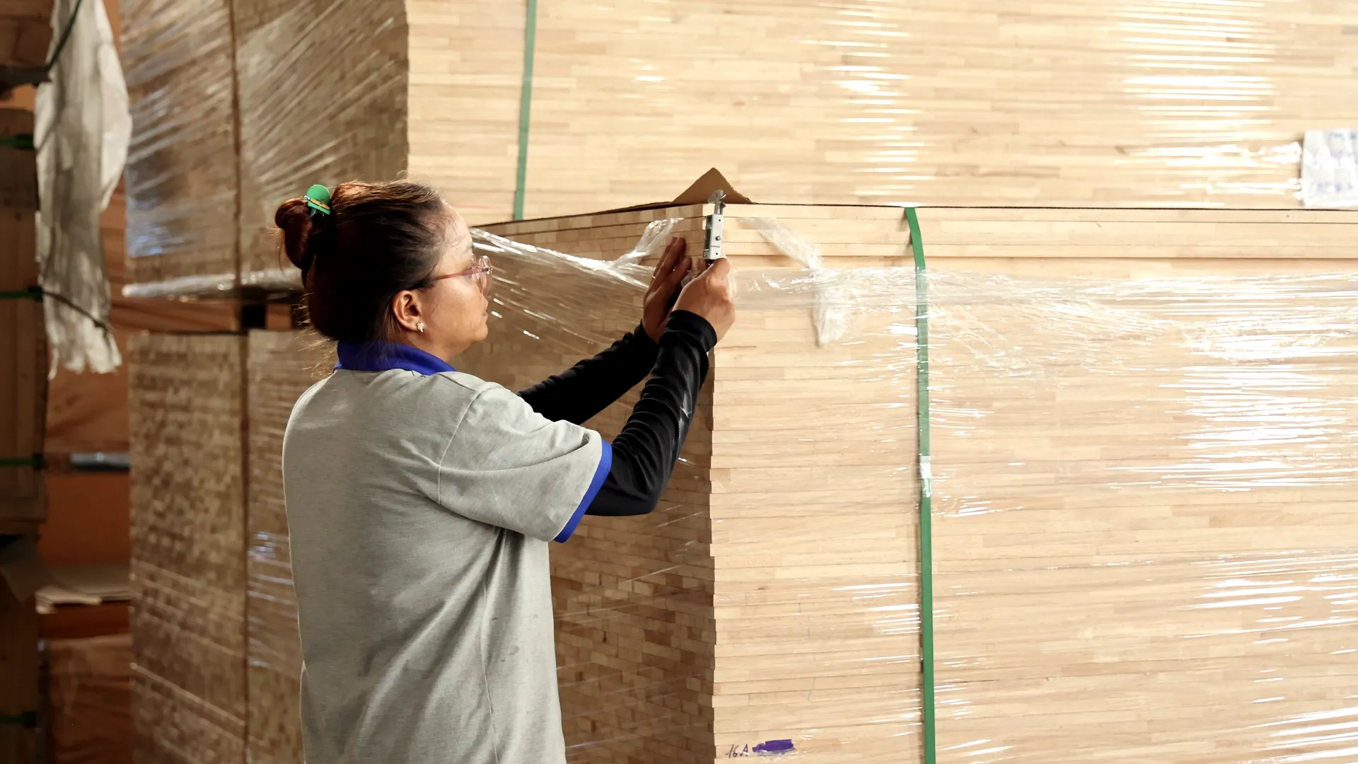 A worker checking wrapped panel stock against the order